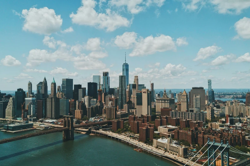 Vista aérea de la ciudad de Nueva York con el Puente de Brooklyn y rascacielos bajo un cielo azul con nubes. Mercurium Investech guía a inversores sudamericanos, incluyendo ecuatorianos, para invertir en la bolsa de EE.UU., como el S&P 500 y ETFs